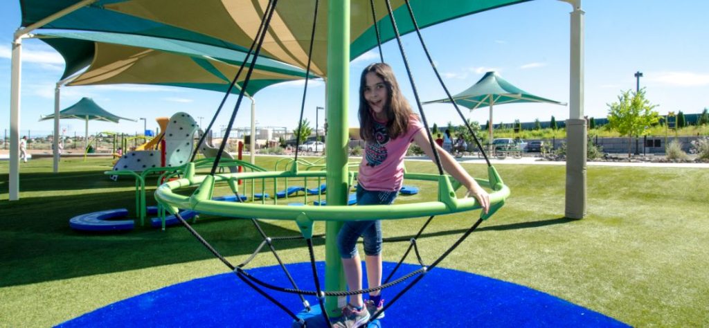 A child playing in a playground done with artificial grass.