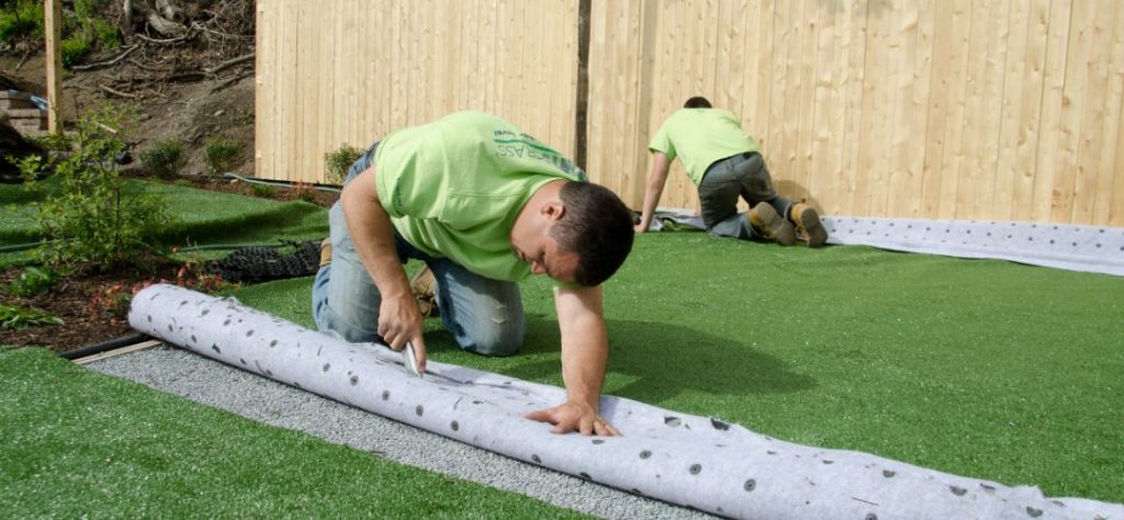 Artificial turf being installed to create a calming backyard.